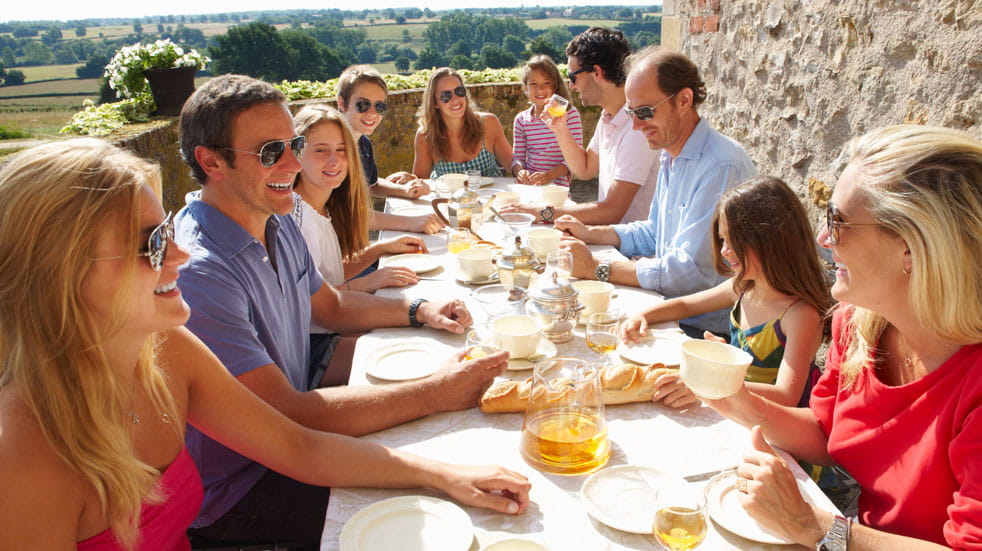 An extended family has breakfast in the sun
